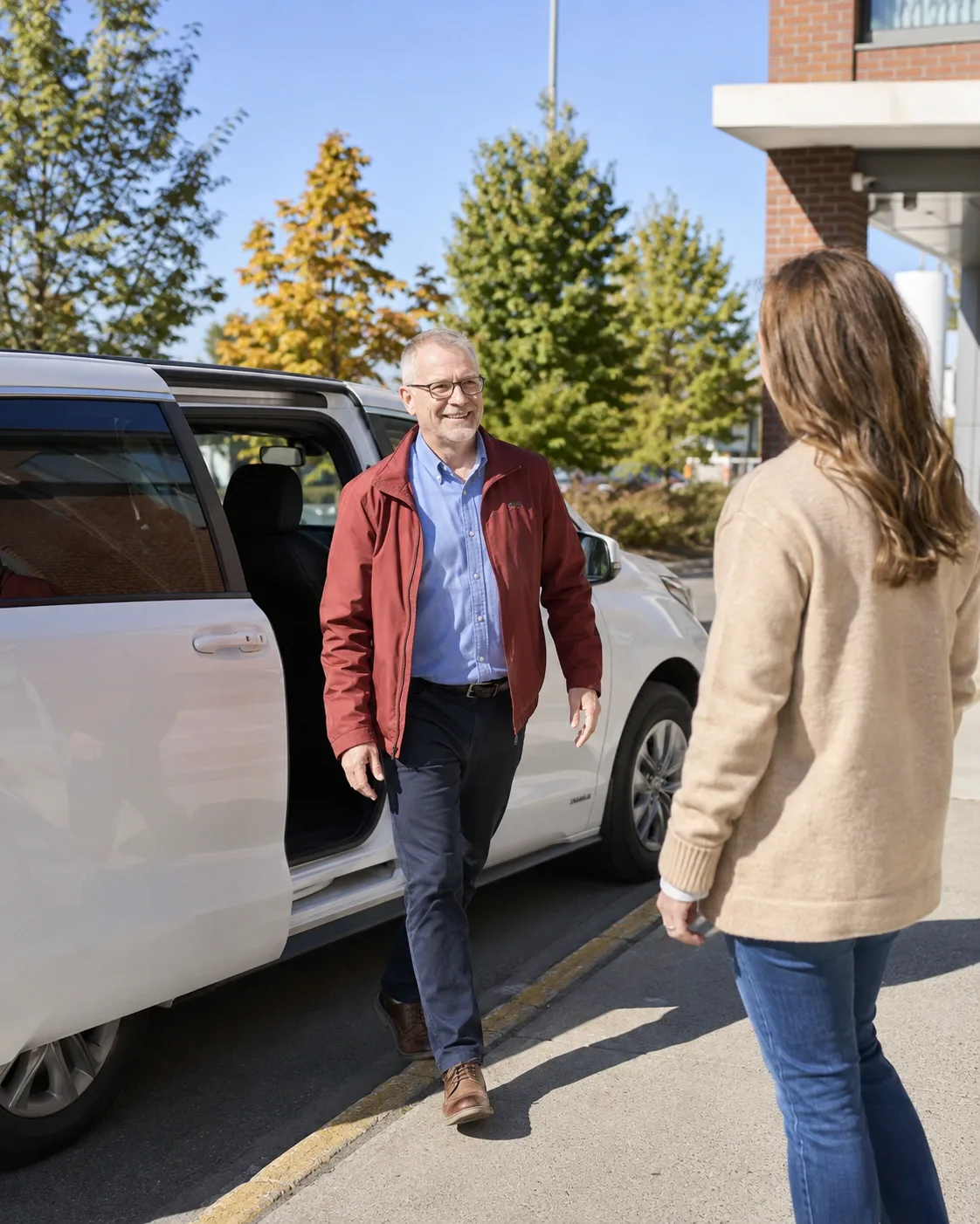 Un chauffeur de navette accueille une cliente à l’extérieur