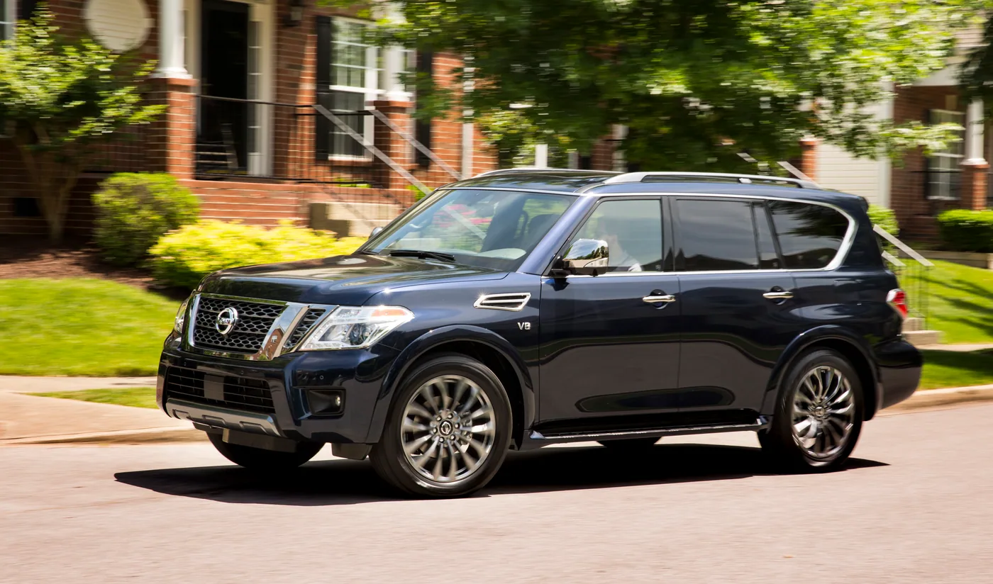 Nissan Armada 2020 bleu nuit roulant dans une rue résidentielle bordée de maisons en brique