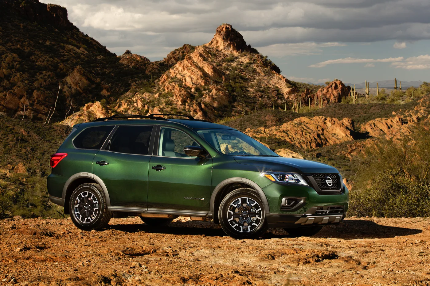 Nissan Pathfinder Rock Creek vert foncé, vue de profil, dans un paysage désertique rocheux