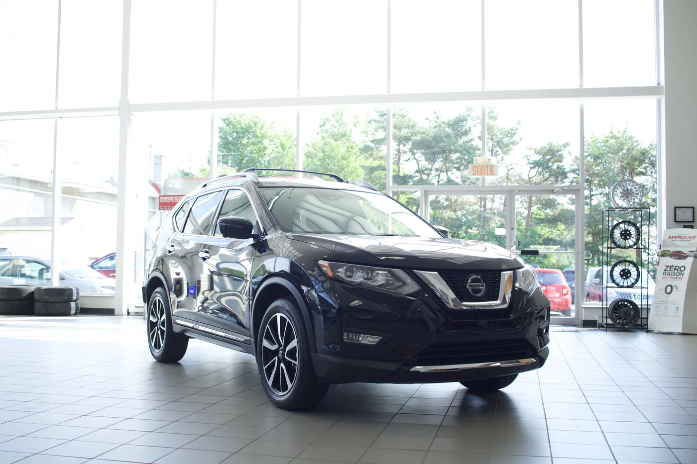 Nissan Rogue noir en trois quarts avant dans une salle d'exposition vitrée