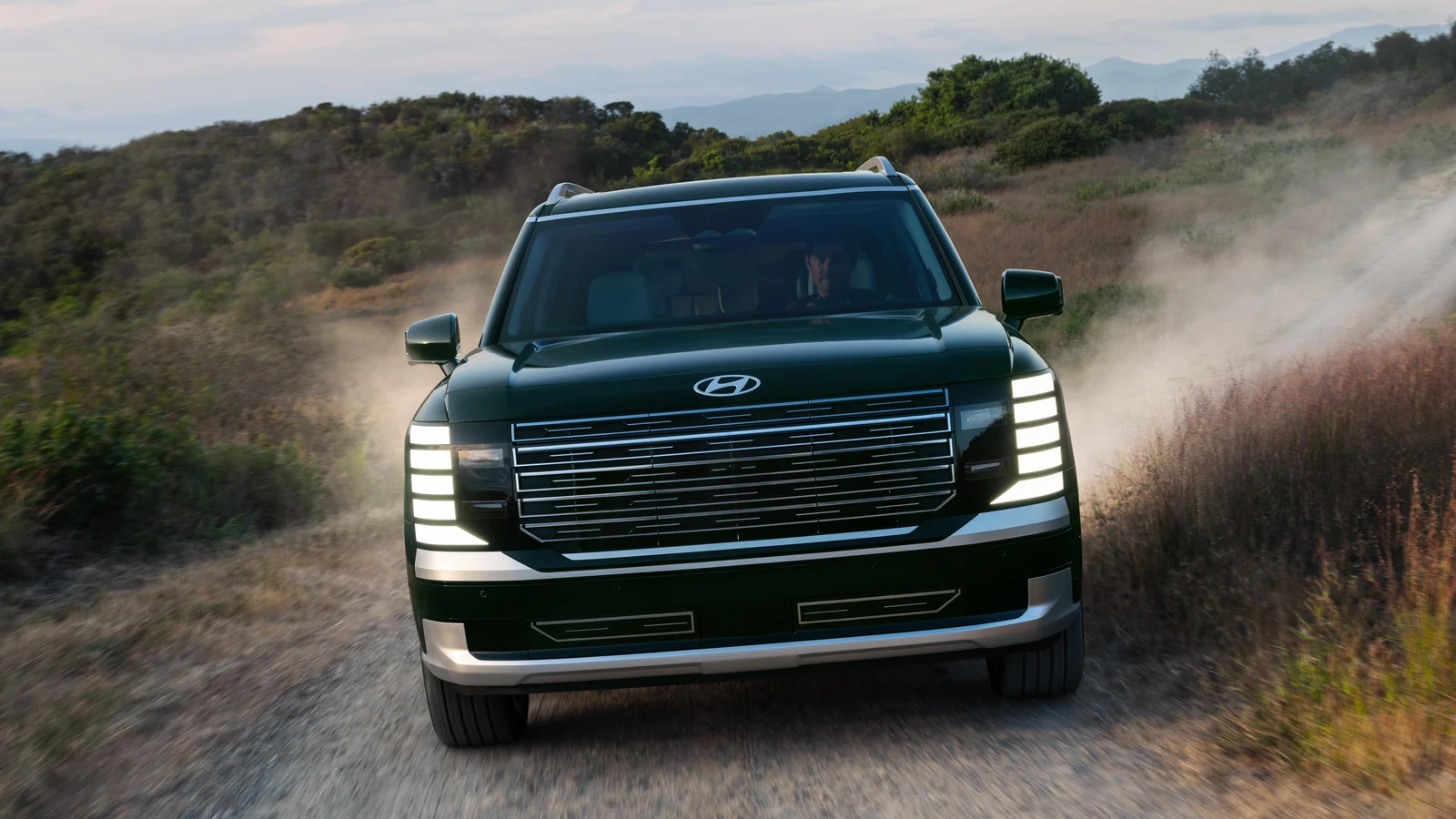 Hyundai Palisade 2026 vu de face sur un chemin de terre, nuage de poussière derrière lui