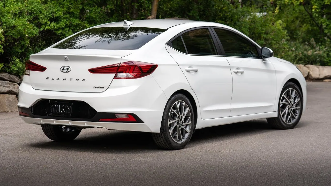 Hyundai Elantra blanche vue de trois quarts arrière, garée devant des arbres