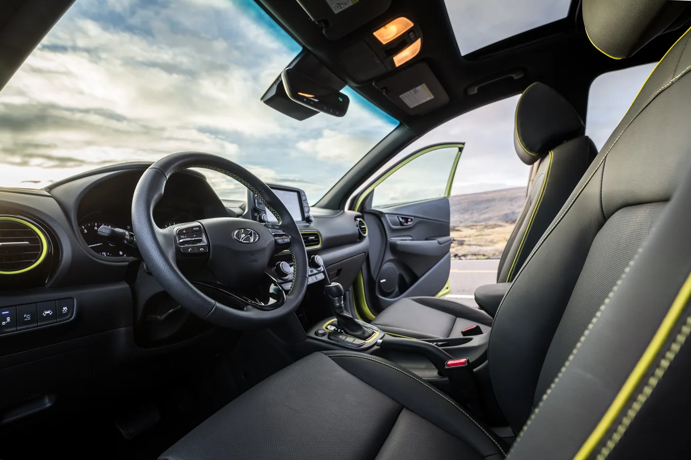 Habitacle du Hyundai Kona : volant, écran, sièges en cuir noir à surpiqûres vert lime et toit ouvrant