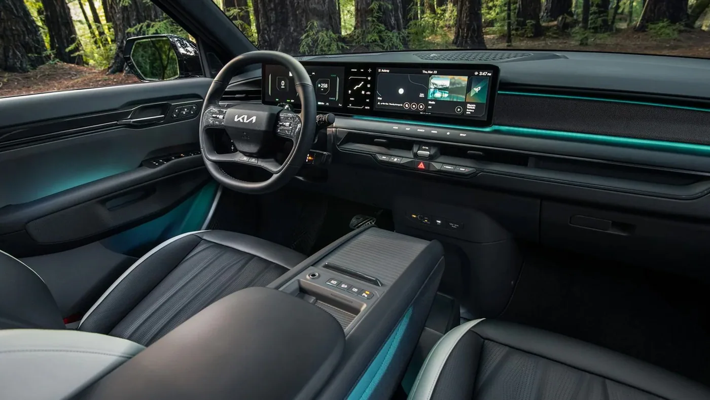 Poste de conduite du Kia EV9 avec volant Kia, grand écran panoramique et éclairage d'ambiance turquoise