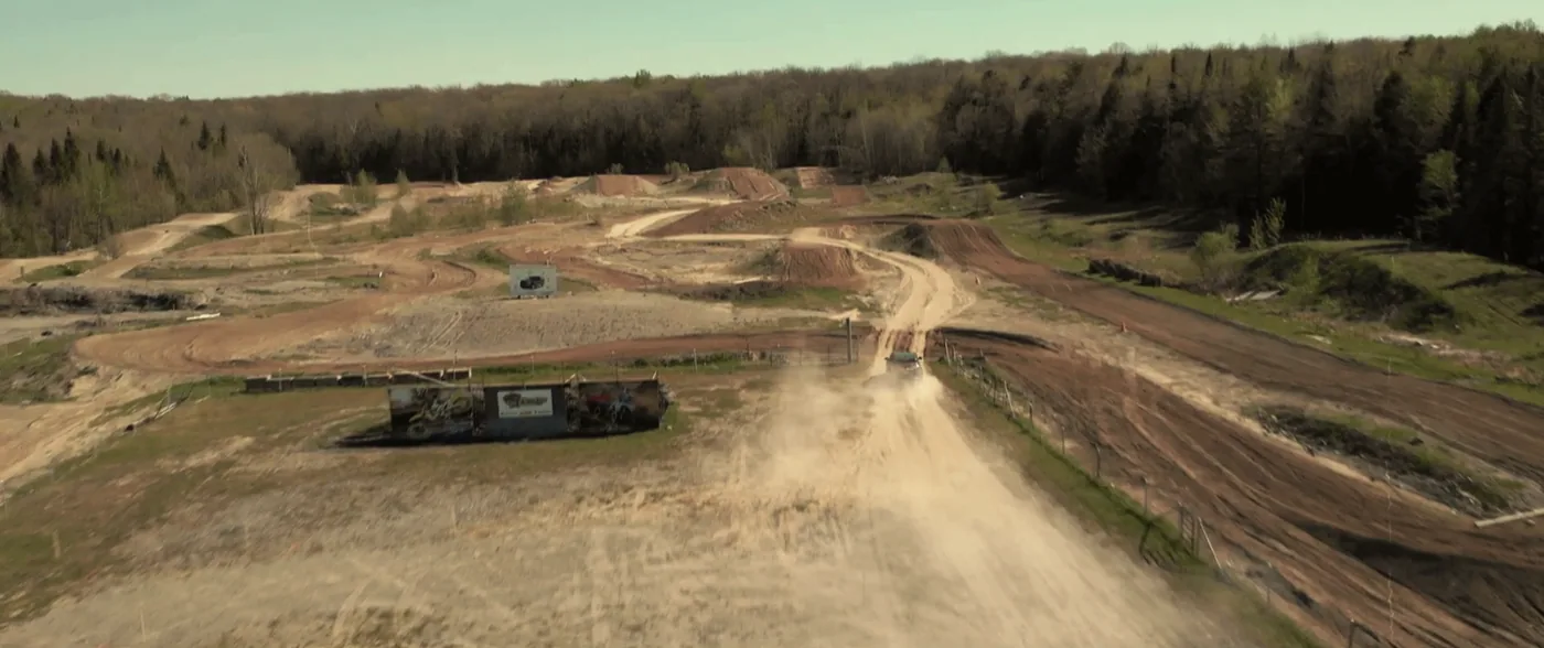 Vue aérienne d'un circuit de terre avec un véhicule qui soulève un nuage de poussière
