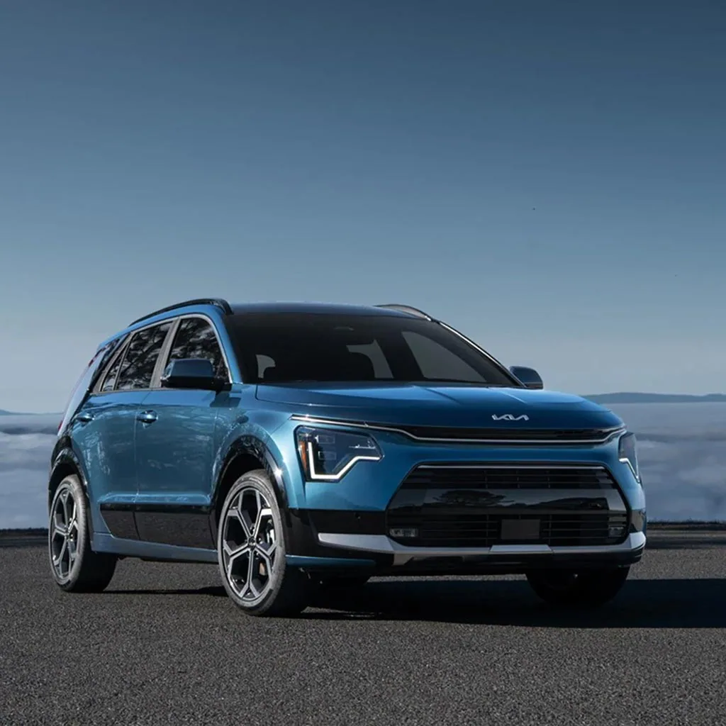 Kia Niro 2023 bleu vu de trois quarts avant au-dessus d'une mer de nuages