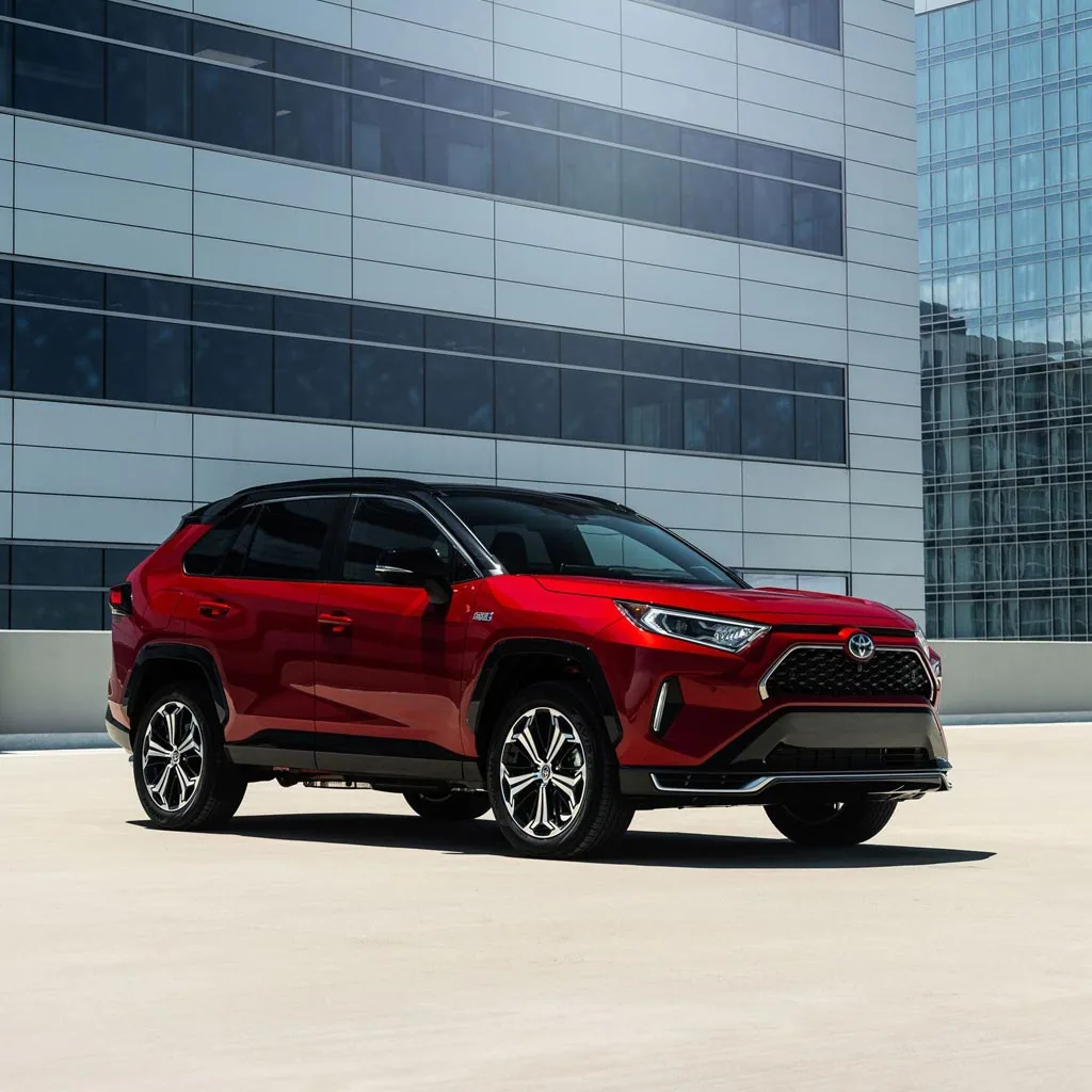 Toyota RAV4 Prime 2023 rouge vu de trois quarts avant devant un immeuble de verre