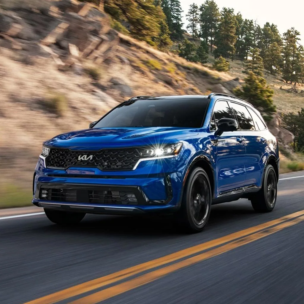 Kia Sorento 2023 bleu en mouvement sur une route de montagne, vue de trois quarts avant