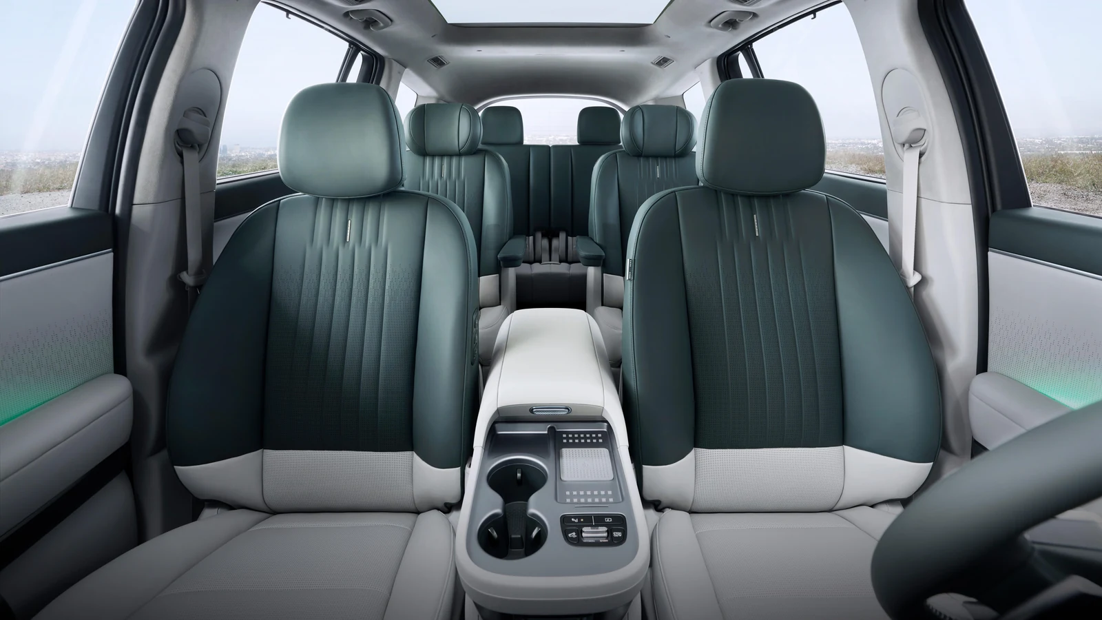 Habitacle du Hyundai IONIQ 9 vu depuis l'avant : sièges verts et gris sur trois rangées, toit vitré