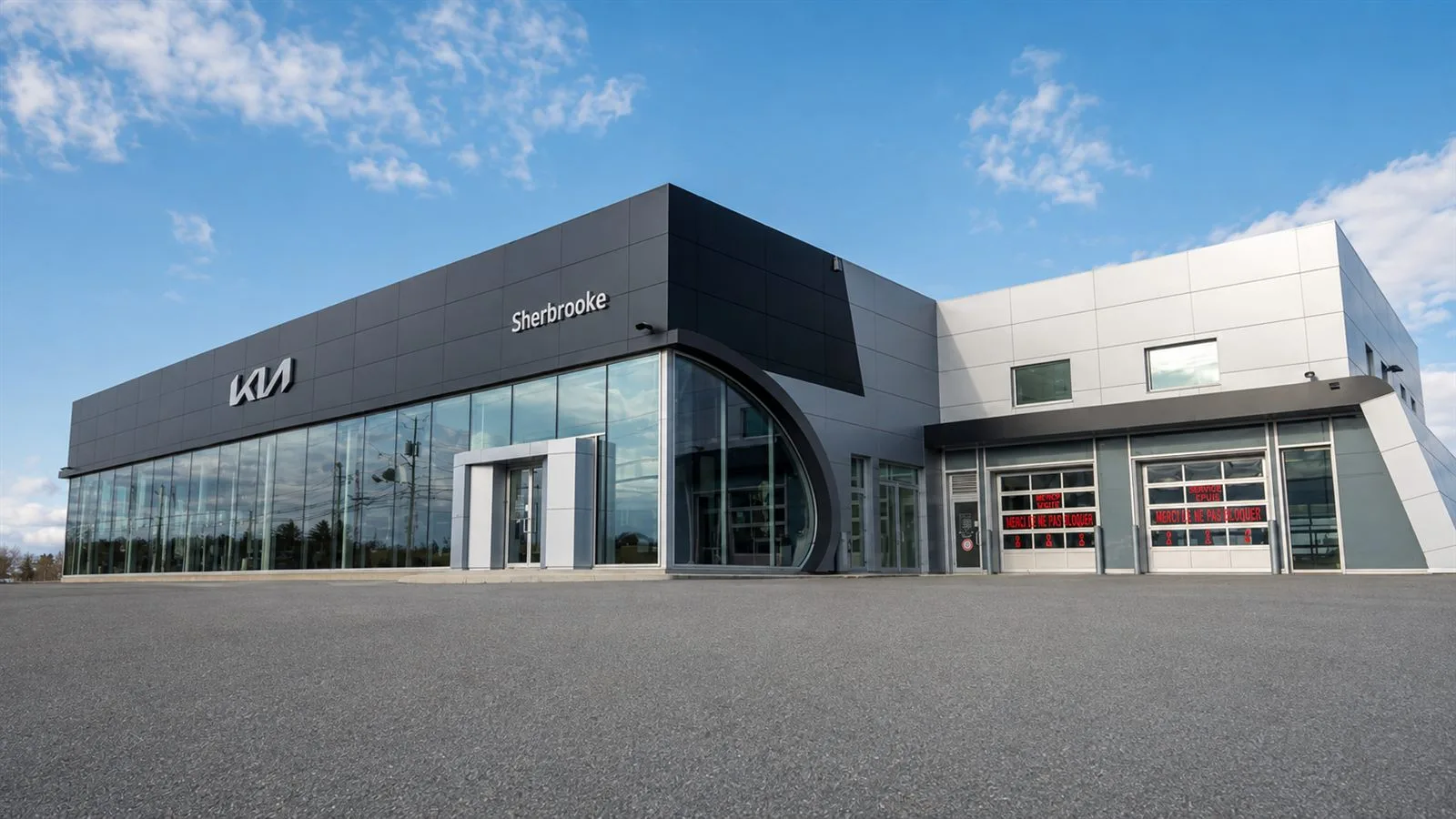 Façade vitrée d'une concession du réseau Beaucage à Sherbrooke sous un ciel bleu, stationnement client au premier plan