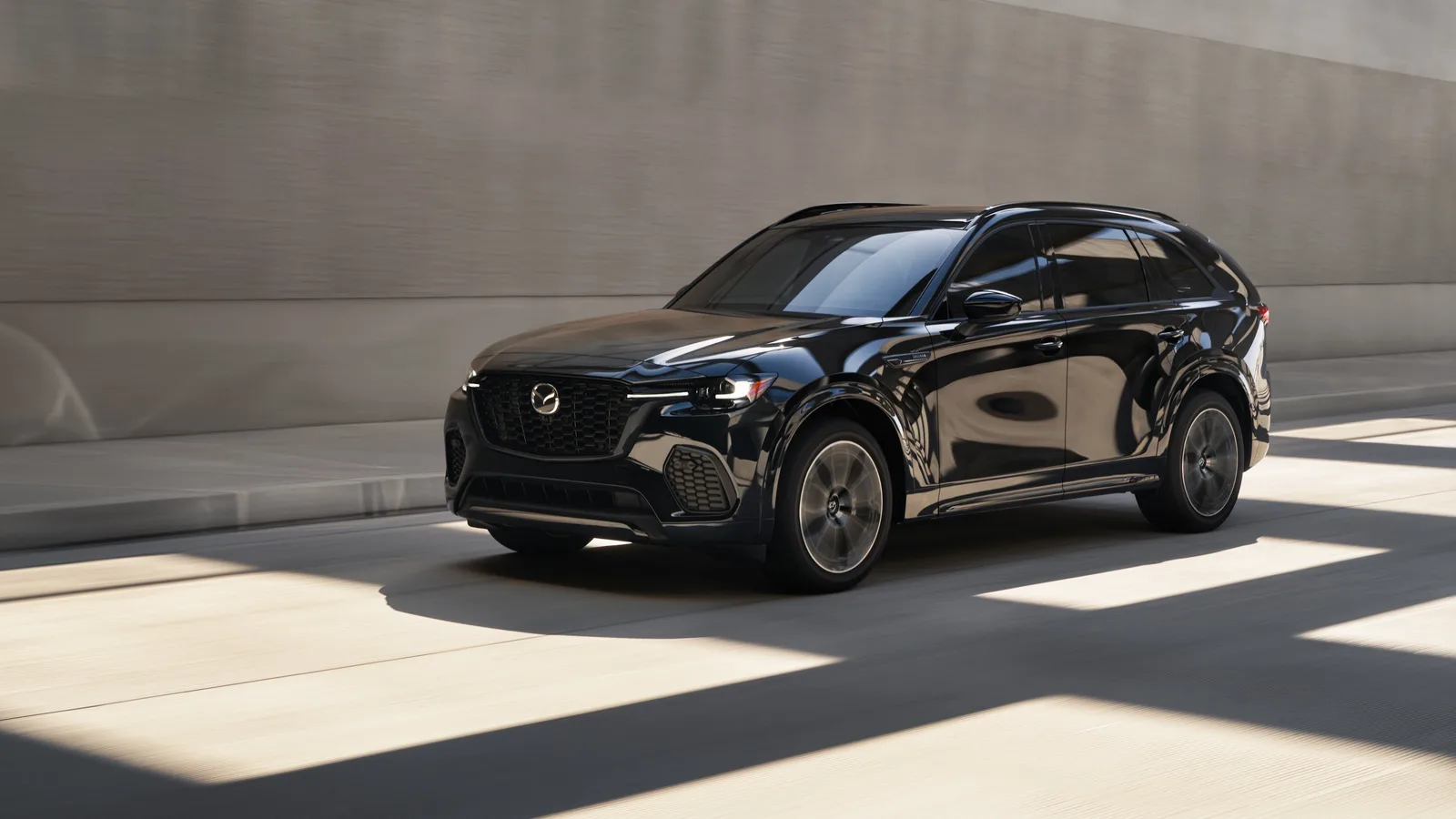 Mazda CX-70 noir en mouvement, vu de trois quarts avant, calandre et emblème Mazda visibles