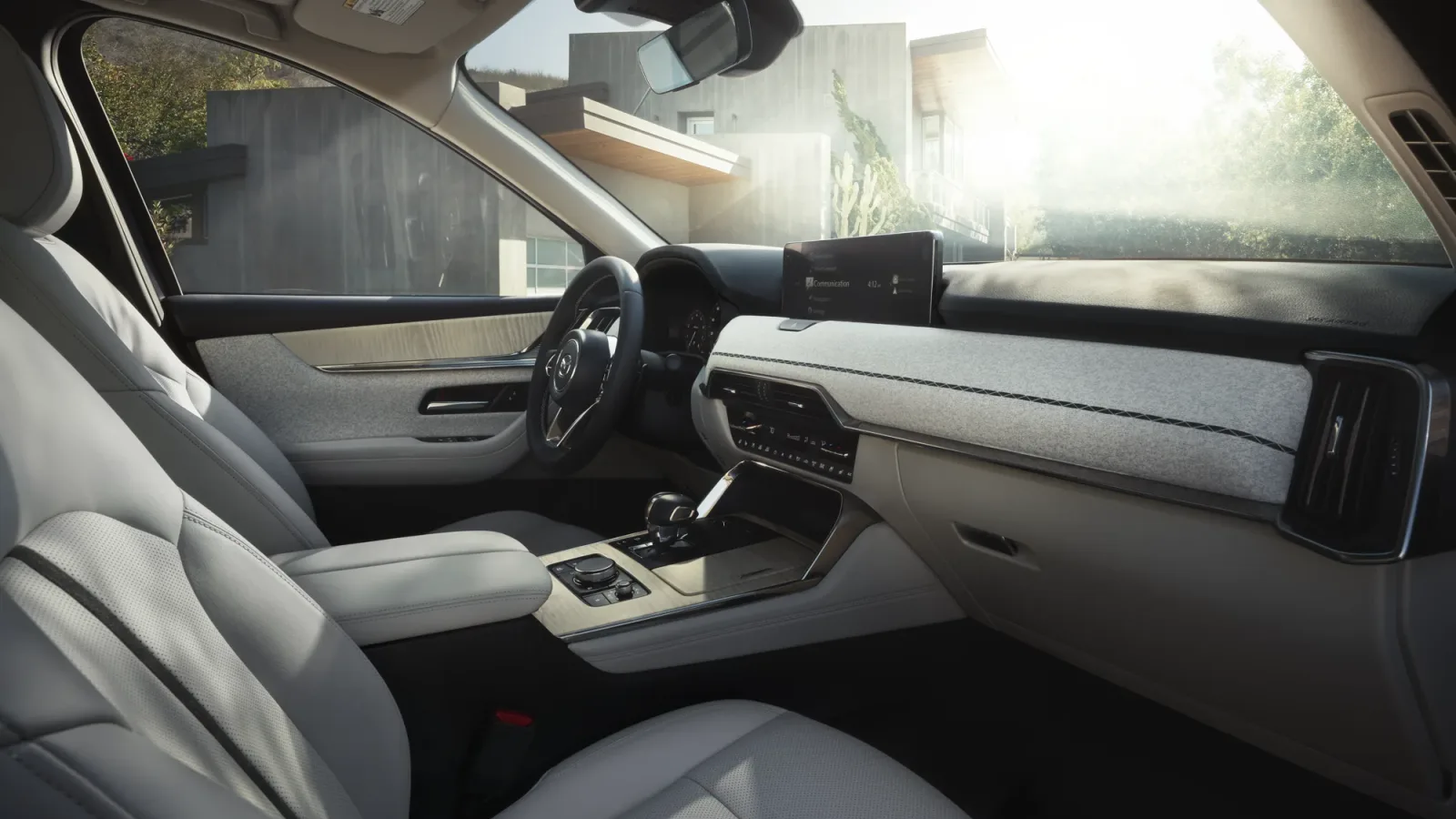 Habitacle d'un Mazda CX-90, planche de bord, volant et écran d'infodivertissement vus depuis le siège passager