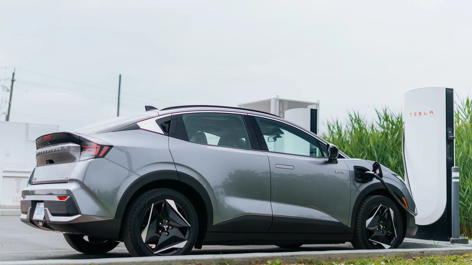 Mitsubishi Eclipse Sportback EV gris vu de trois quarts arrière, en recharge à une borne rapide Tesla