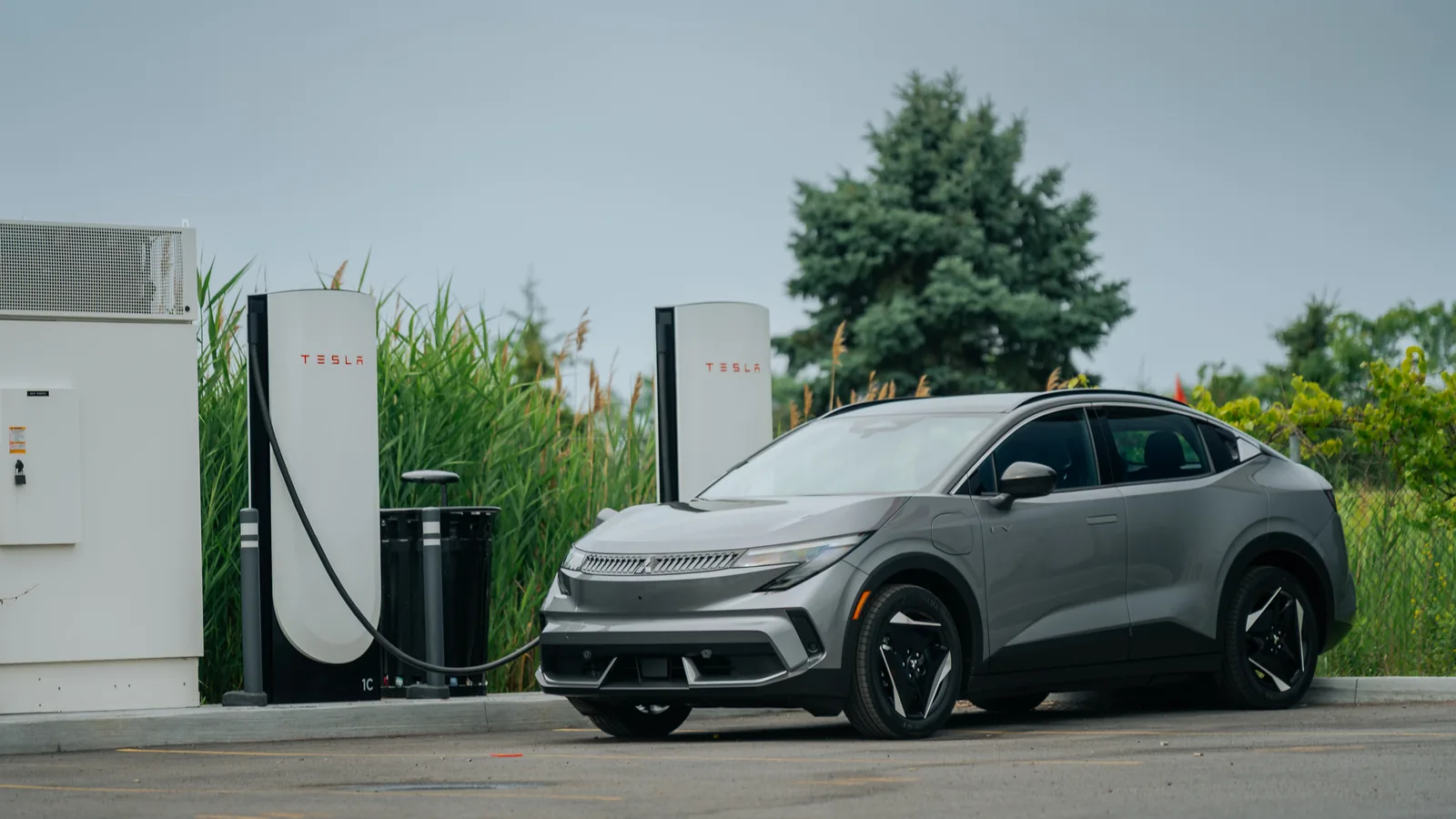 Mitsubishi Eclipse Sportback EV gris stationné devant deux bornes de recharge rapide Tesla