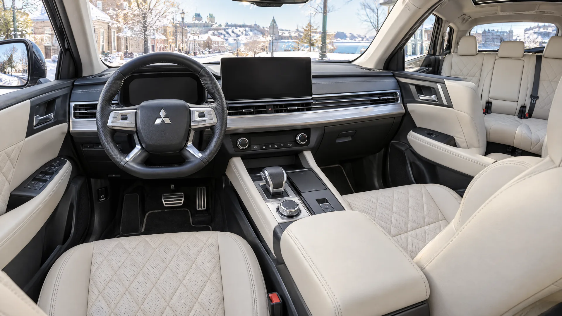 Habitacle du Mitsubishi Outlander PHEV 2026 vu depuis le siège passager avant, écran central éteint, sellerie pâle, deuxième rangée visible
