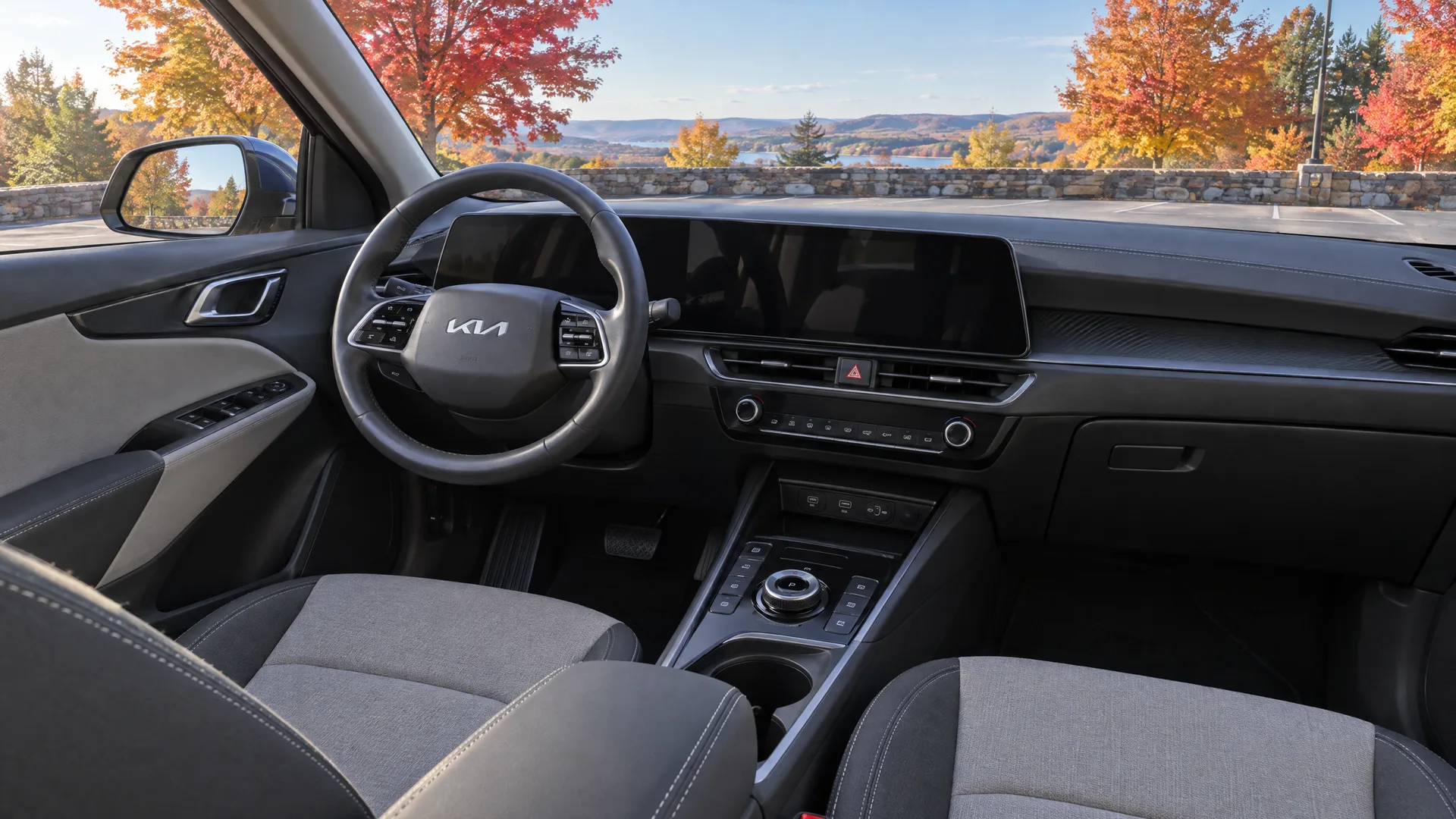 Habitacle d'un Kia Niro 2026 vu depuis le siège passager, écran central éteint, sellerie deux tons, stationnement d'automne par le pare-brise