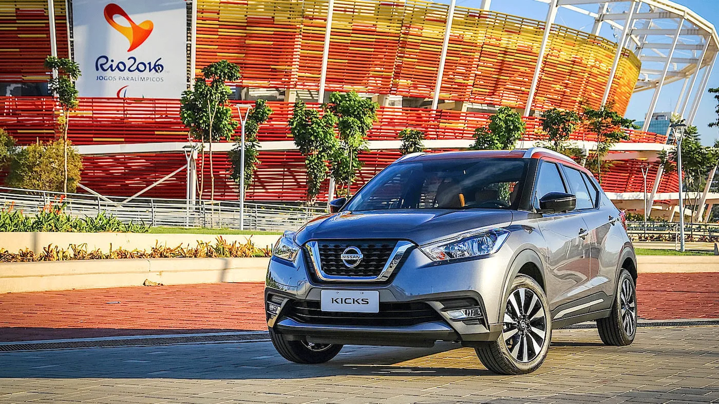 Nissan Kicks argent vu de trois quarts avant devant un stade de Rio de Janeiro orné de l'affiche des Jeux paralympiques de 2016