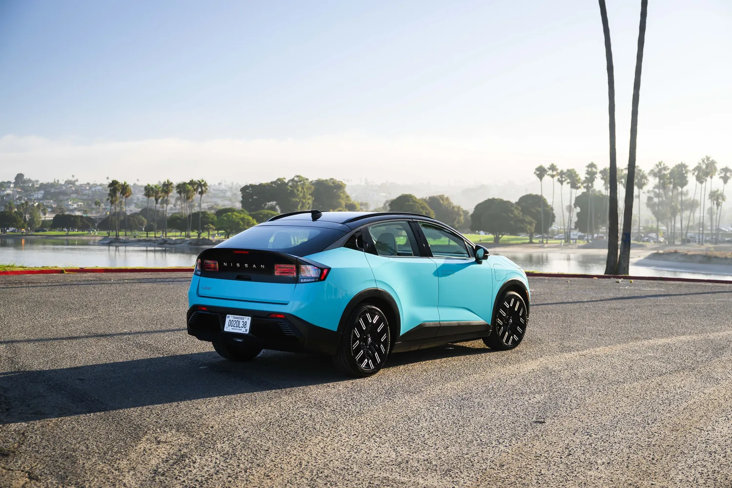 Nissan LEAF bleu clair vue de l'arrière au bord d'un lac, feux en bandeau allumés