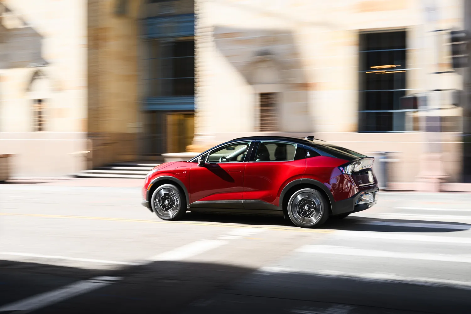 Nissan LEAF rouge vue de trois quarts arrière devant une maison de style ancien