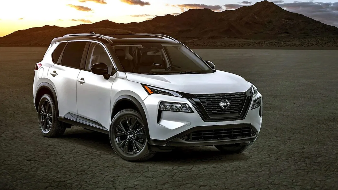 Nissan Rogue 2023 blanc à toit noir, vue de trois quarts avant, dans un désert au coucher du soleil