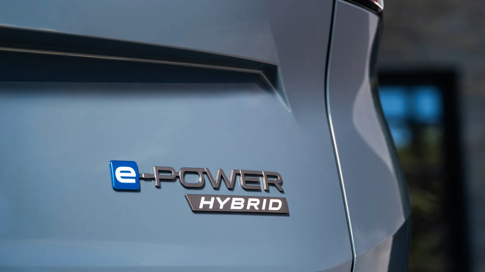 Gros plan sur l'écusson e-POWER Hybrid à l'arrière d'un Nissan Rogue hybride 2027 bleu-gris