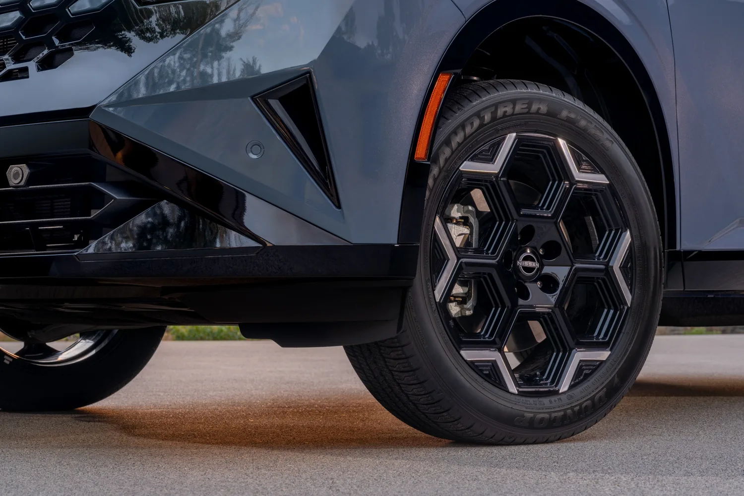 Gros plan sur la jante noire à branches hexagonales et le pneu d'un Nissan Rogue hybride 2027 bleu