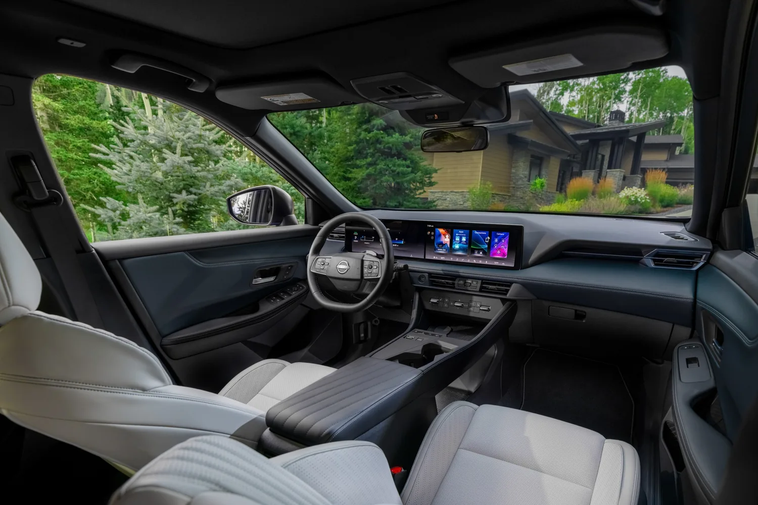 Habitacle clair d'un Nissan Rogue hybride 2027 vu depuis la banquette arrière, avec l'écran de la planche de bord