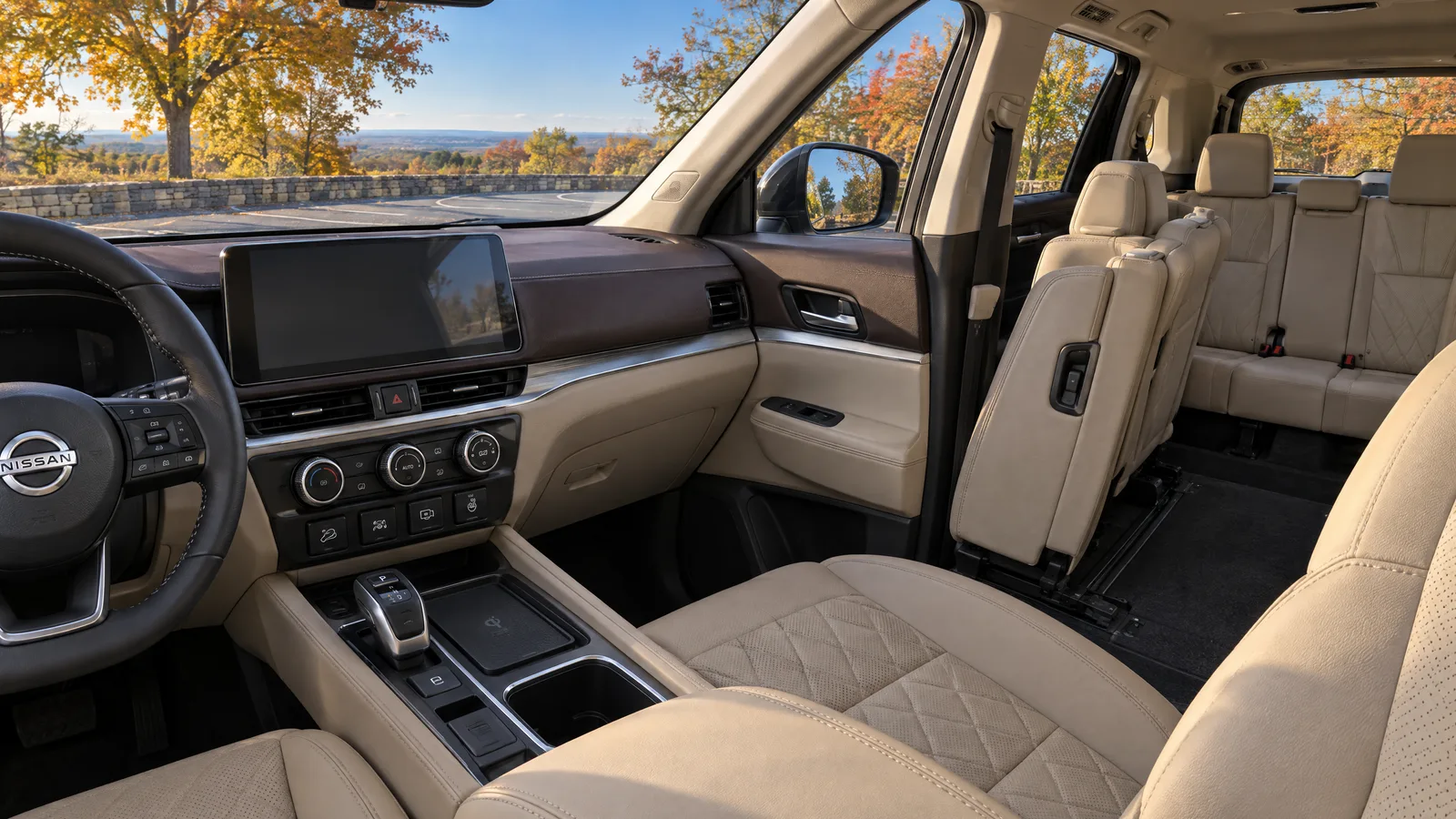 Habitacle d'un Nissan Pathfinder 2026 vu depuis le siège passager, écran central en veille, sellerie de cuir beige, deuxième et troisième rangées visibles