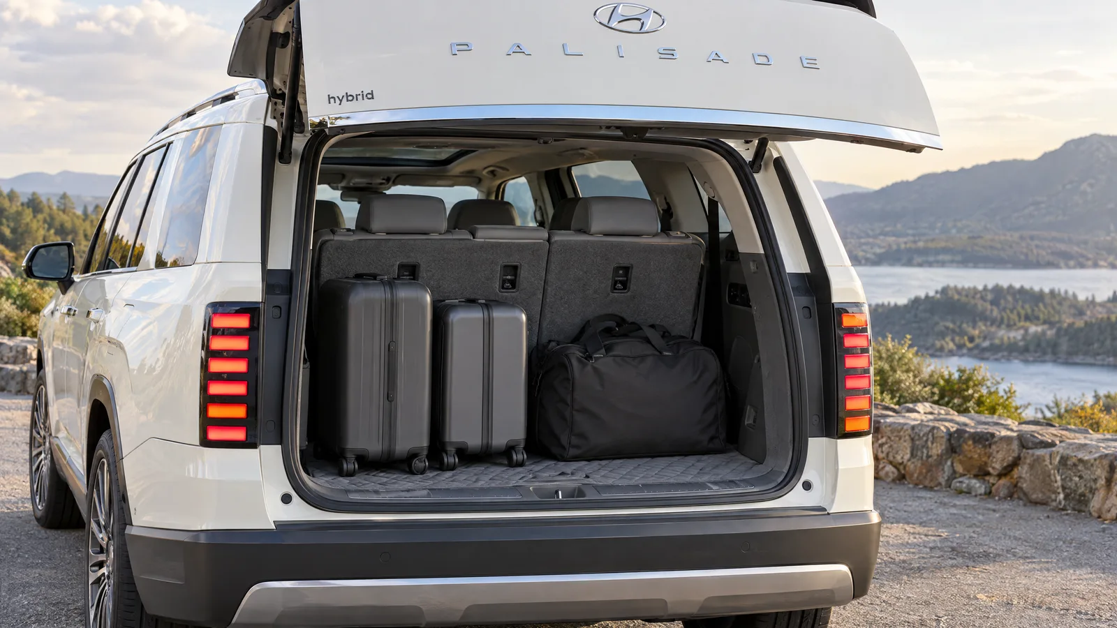 Coffre ouvert d'un Hyundai Palisade 2026 blanc avec la troisième rangée relevée, deux valises et un sac de sport posés derrière la banquette
