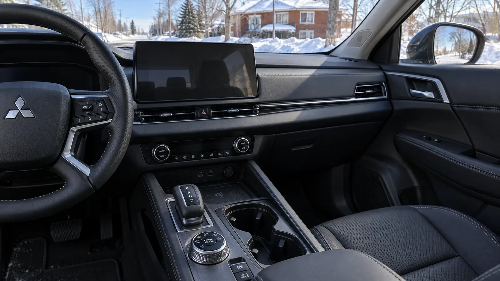 Habitacle d'un Mitsubishi Outlander vu depuis le siège passager, molette des modes de conduite sur la console, écran central en veille