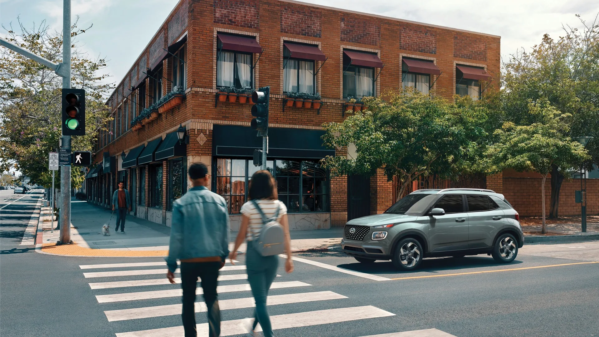 Couple traversant une rue de centre-ville devant un Hyundai Venue 2026 vert