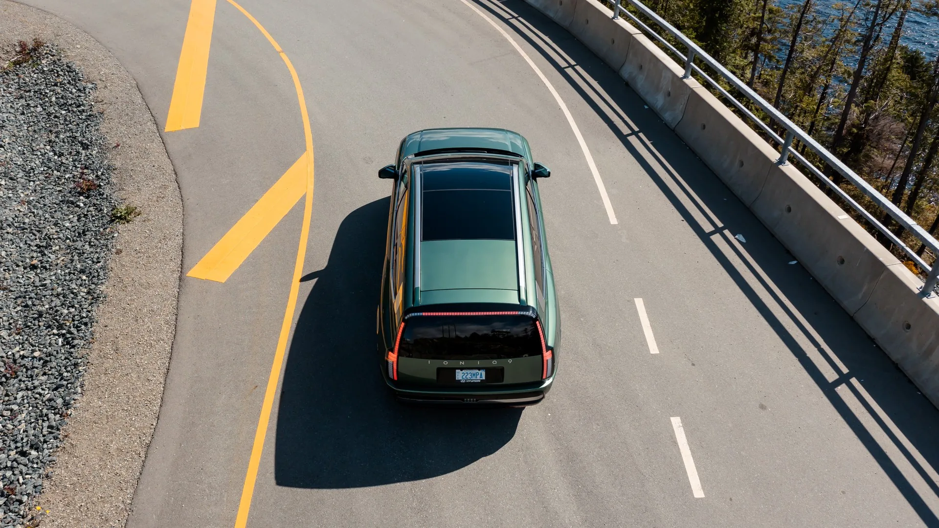 Hyundai IONIQ 9 vert vu du ciel sur une route sinueuse longeant un lac