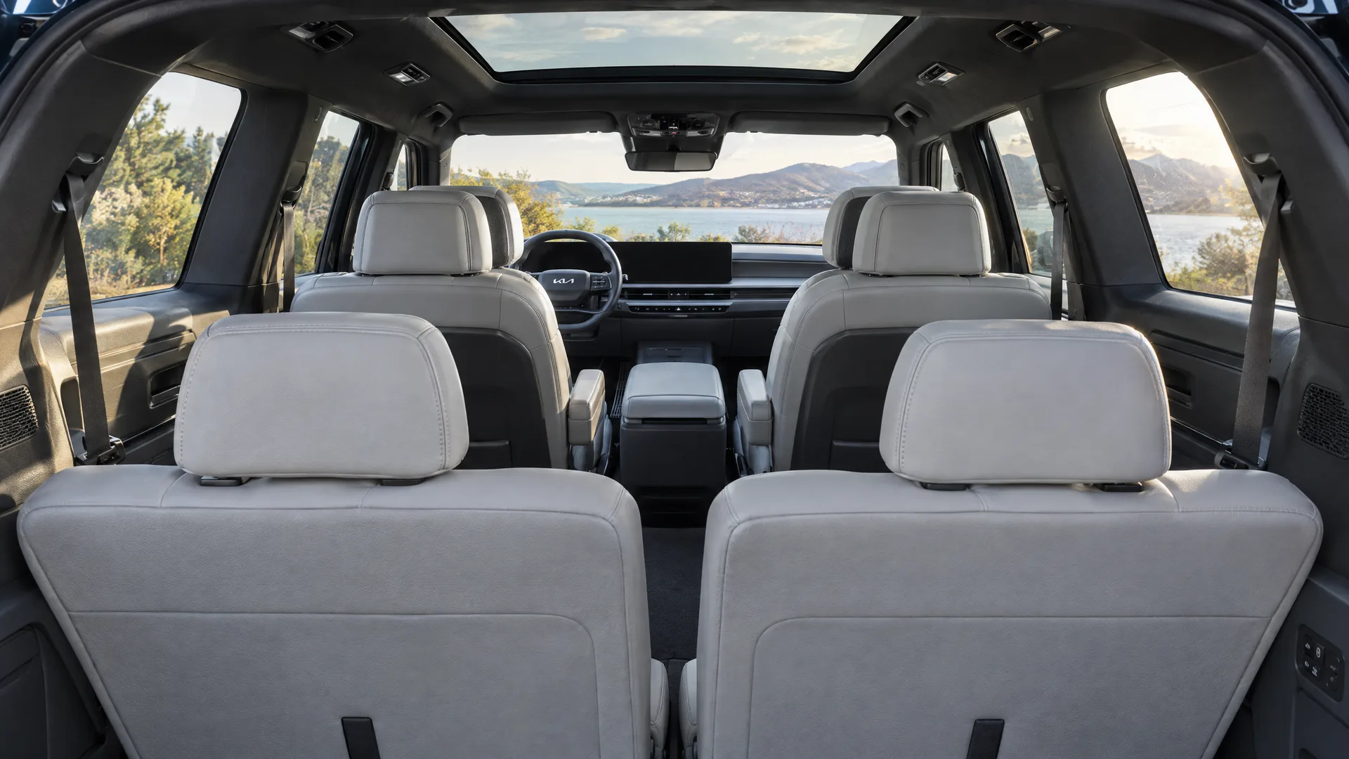 Troisième rangée d'un Kia EV9 2026 vue depuis le hayon ouvert, sellerie gris clair, écran central éteint au loin, lumière d'après-midi par la lunette