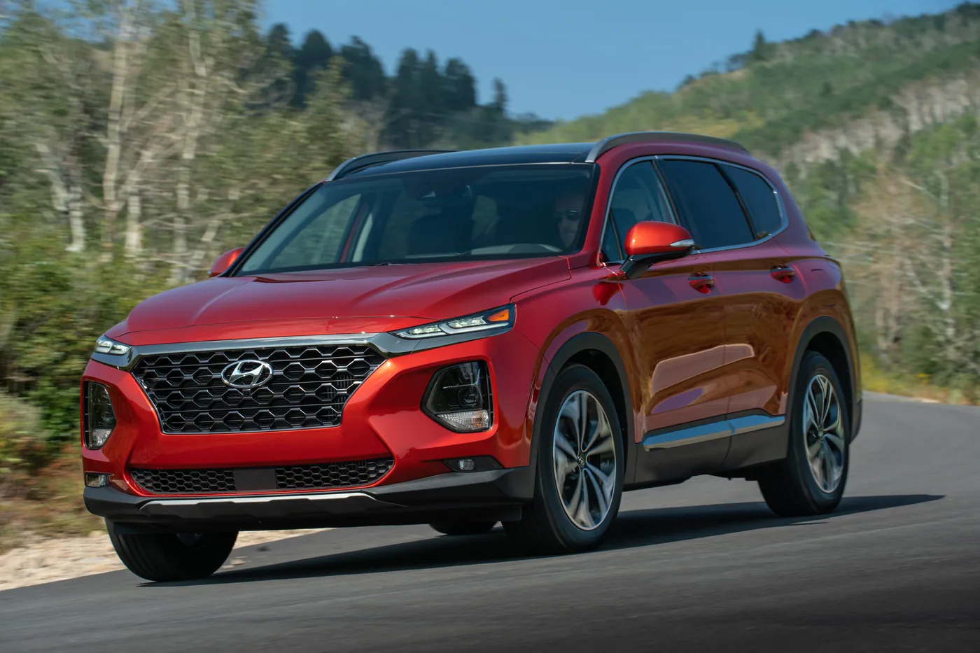 Hyundai Santa Fe rouge en mouvement sur une route de montagne, vue de trois quarts avant