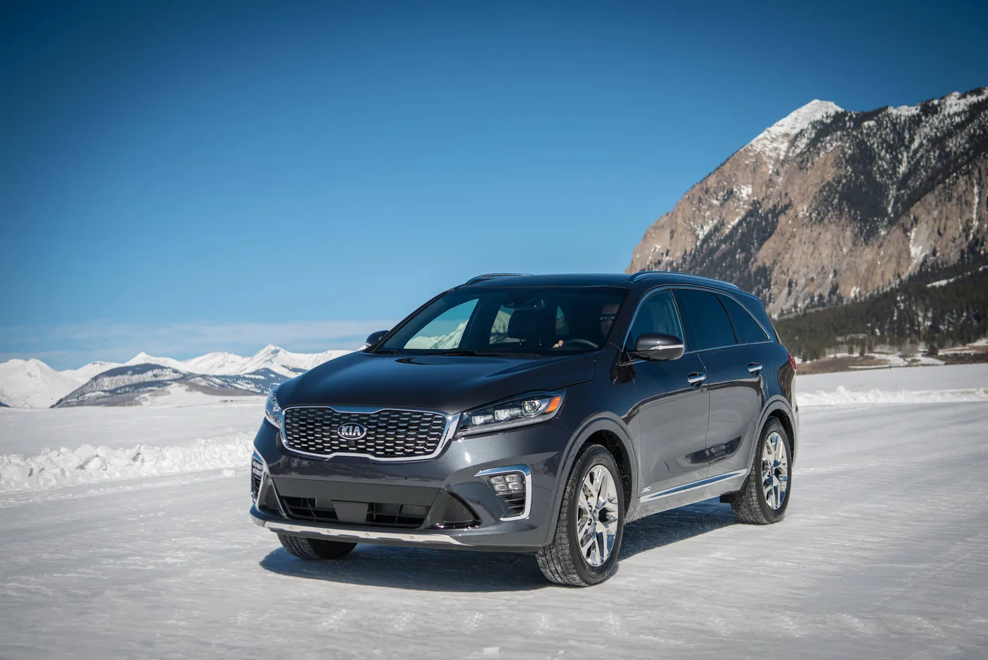 Kia Sorento 2020 gris foncé en trois quarts avant, sur un terrain enneigé devant des montagnes