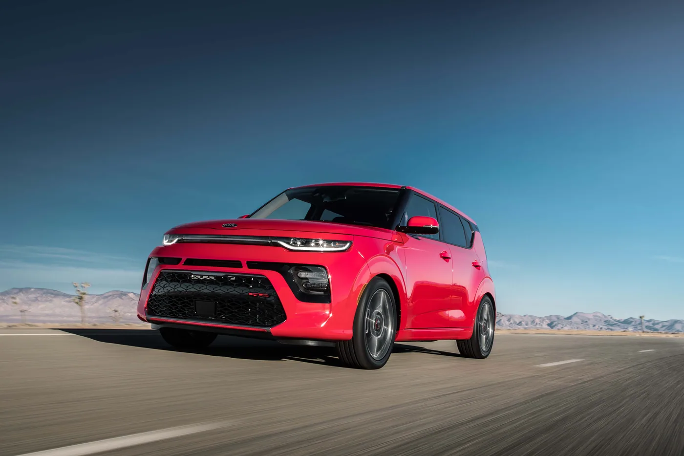 Kia Soul GT 2020 rouge en trois quarts avant, roulant sur une route du désert sous un ciel bleu