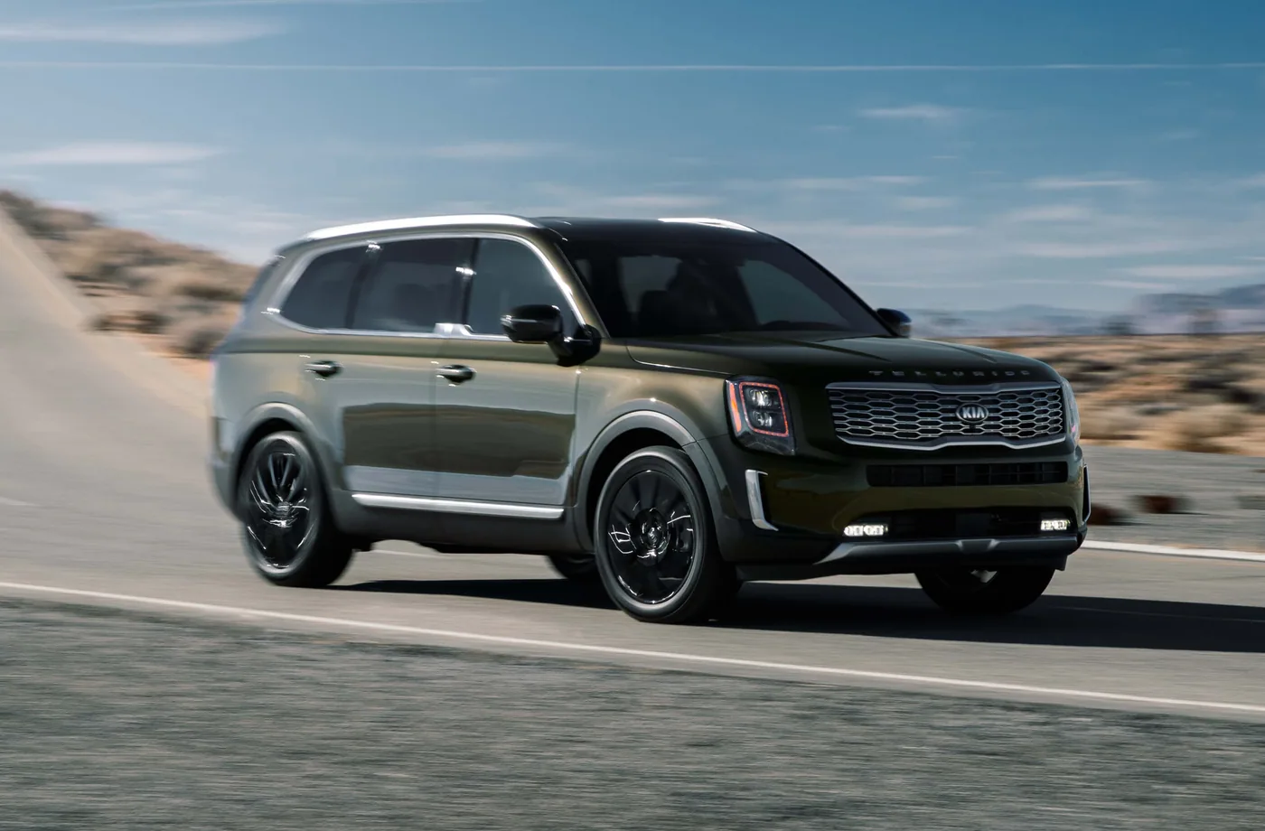 Kia Telluride 2020 vert olive en trois quarts avant, roulant sur une route désertique