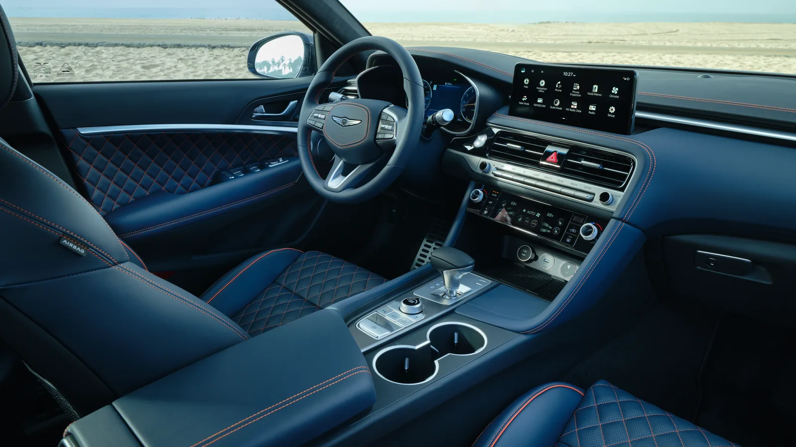 Habitacle bleu d’une Genesis G70 2027, volant à emblème ailé et console centrale vus depuis la portière passager.