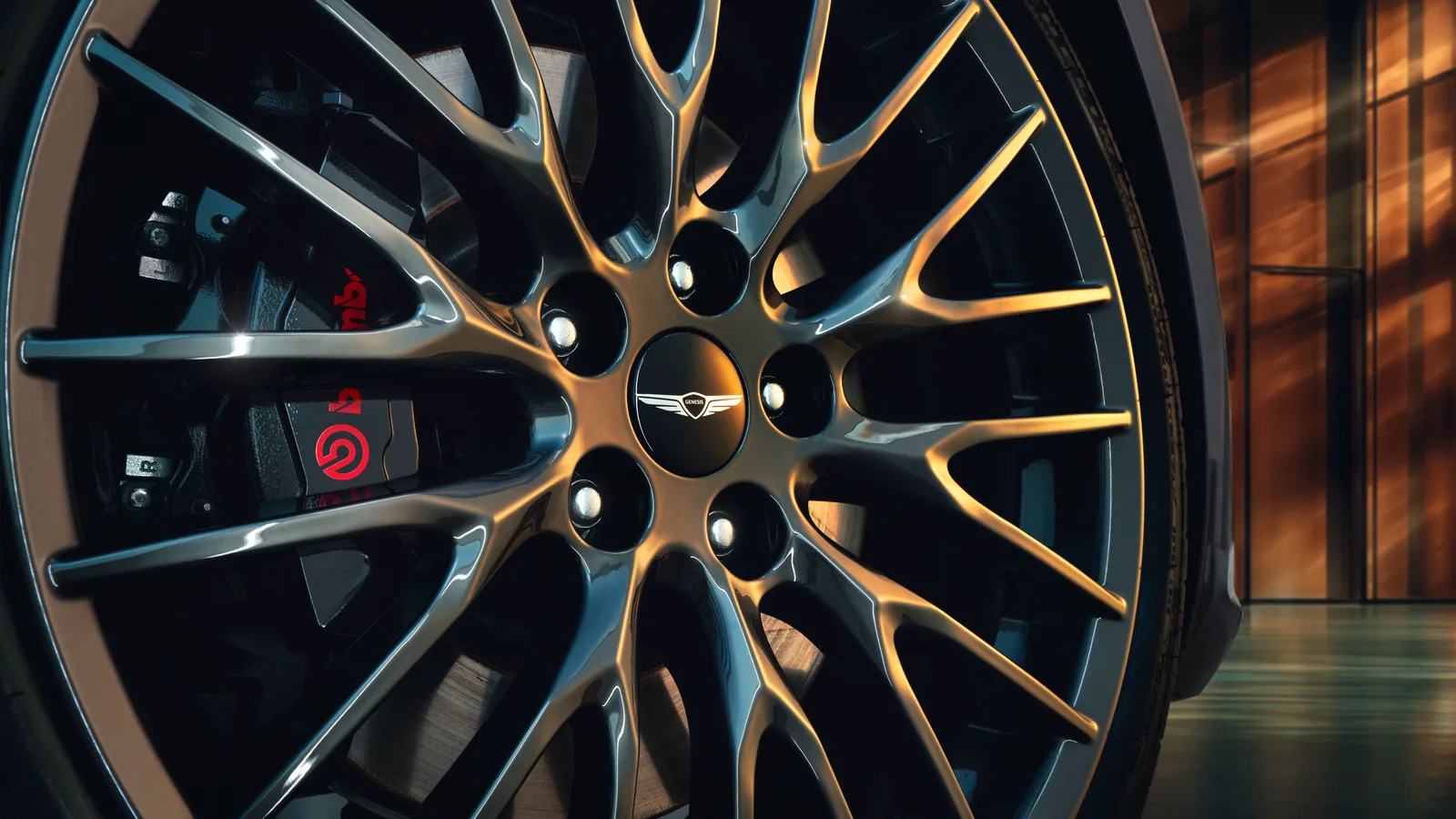 Gros plan sur la jante d’une Genesis G70 Graphite, emblème ailé au centre du moyeu et étrier de frein rouge.