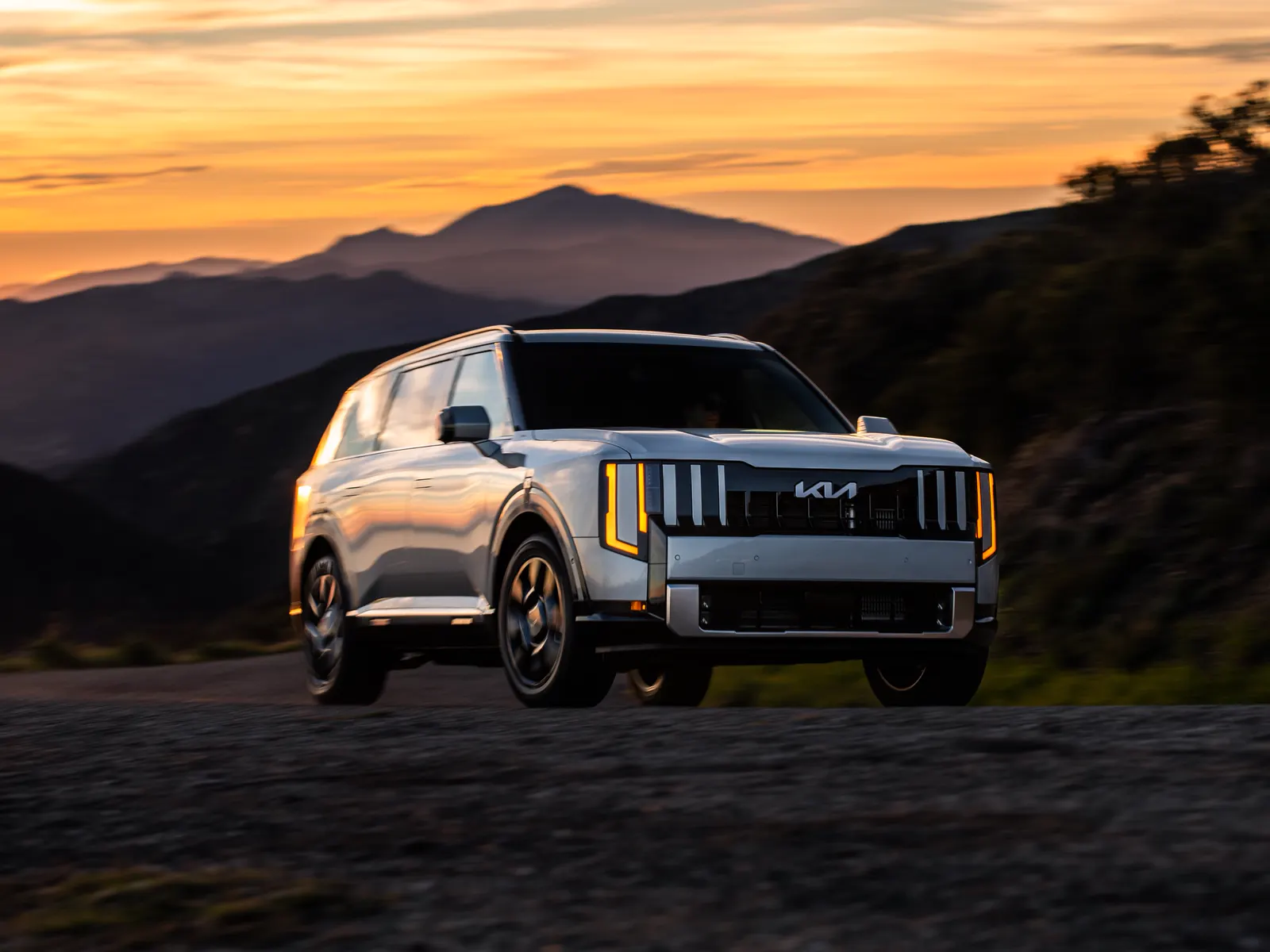 Kia Telluride argent roulant dans les montagnes au coucher du soleil