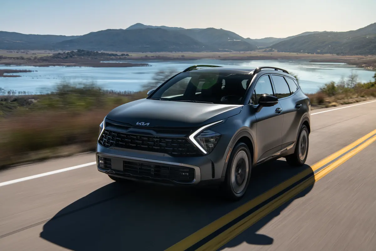 Kia Sportage gris roulant sur une route au bord d’un lac