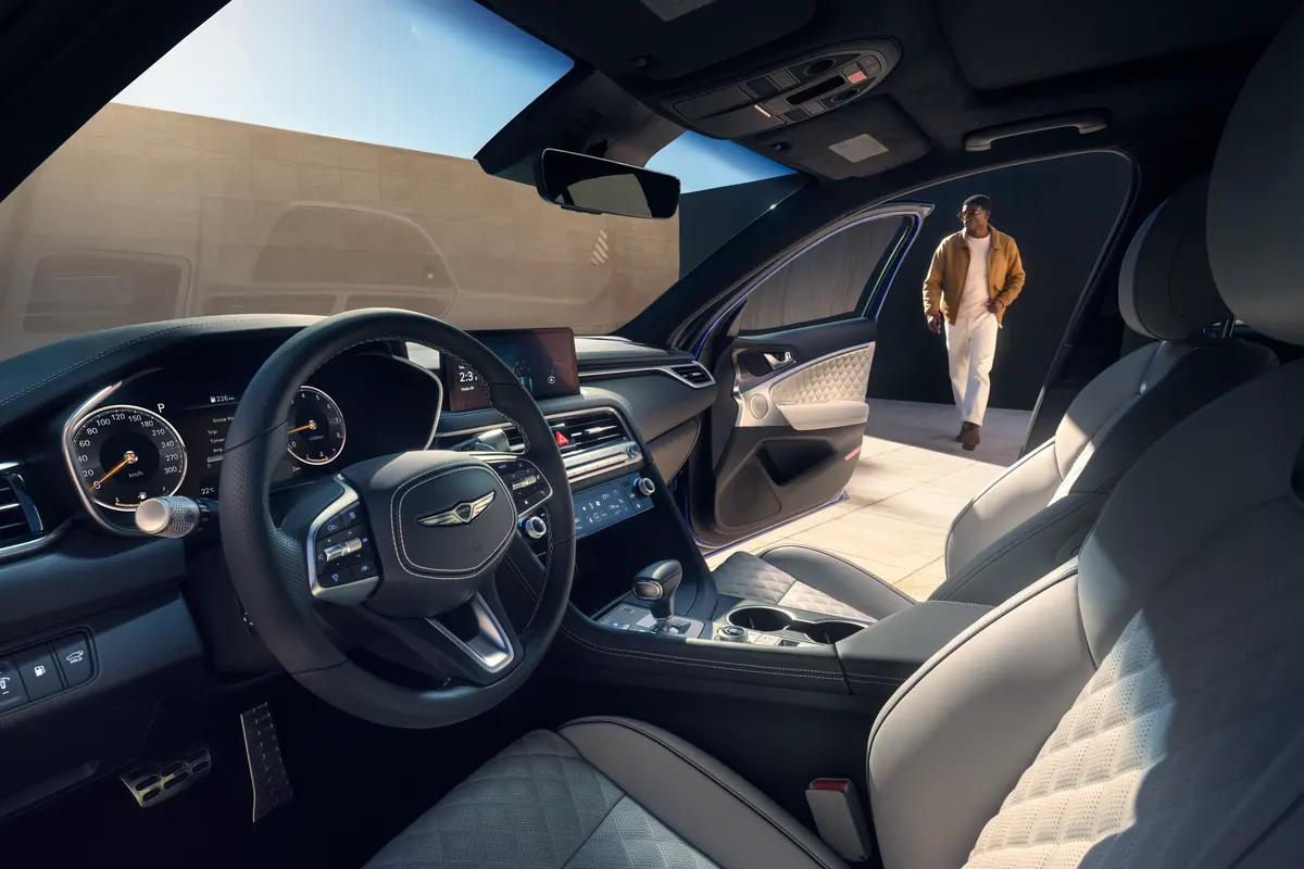 Habitacle aux sièges clairs d’une Genesis G70, portière ouverte sur une journée ensoleillée