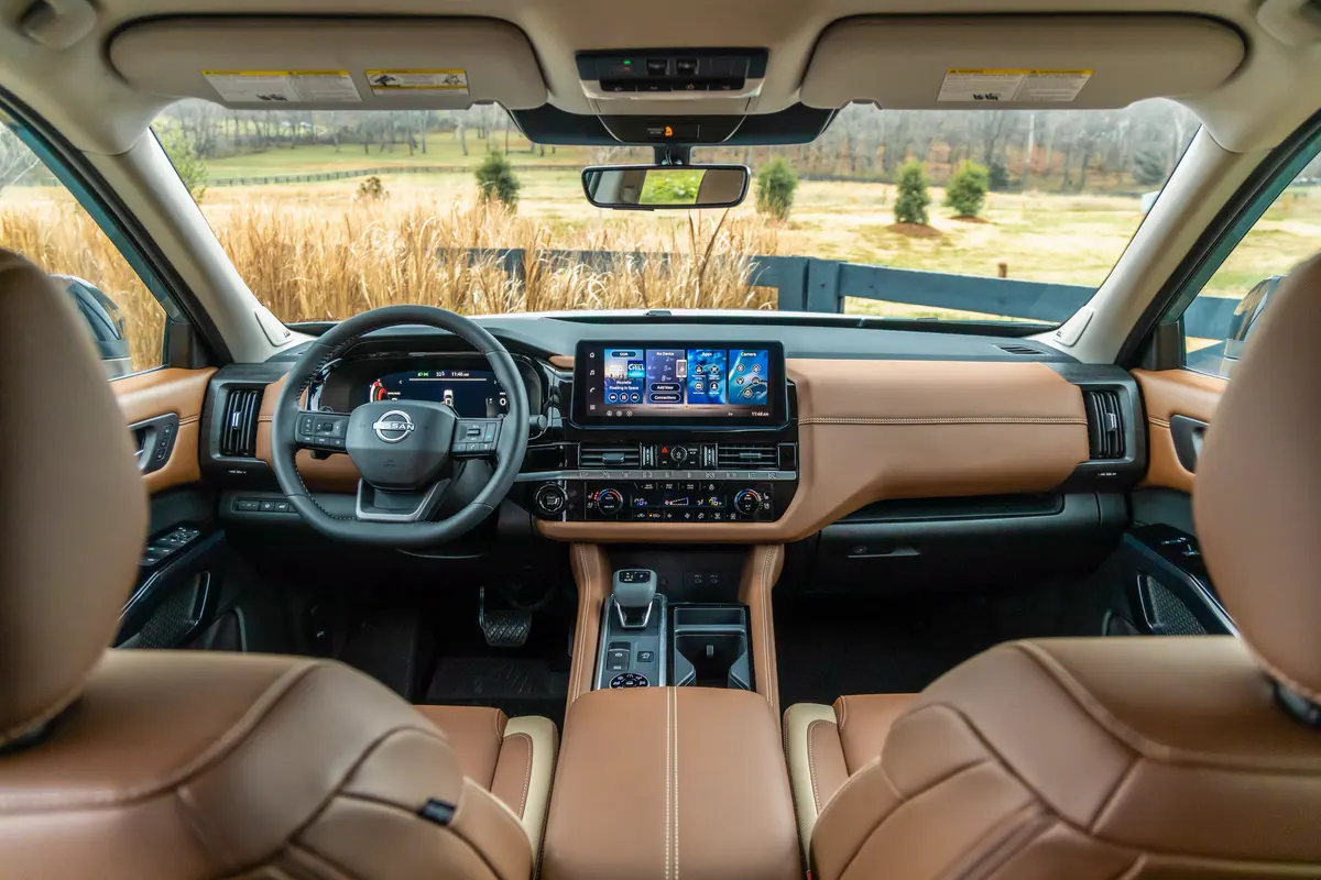 Habitacle d’un Nissan Pathfinder en cuir brun, vue sur un champ