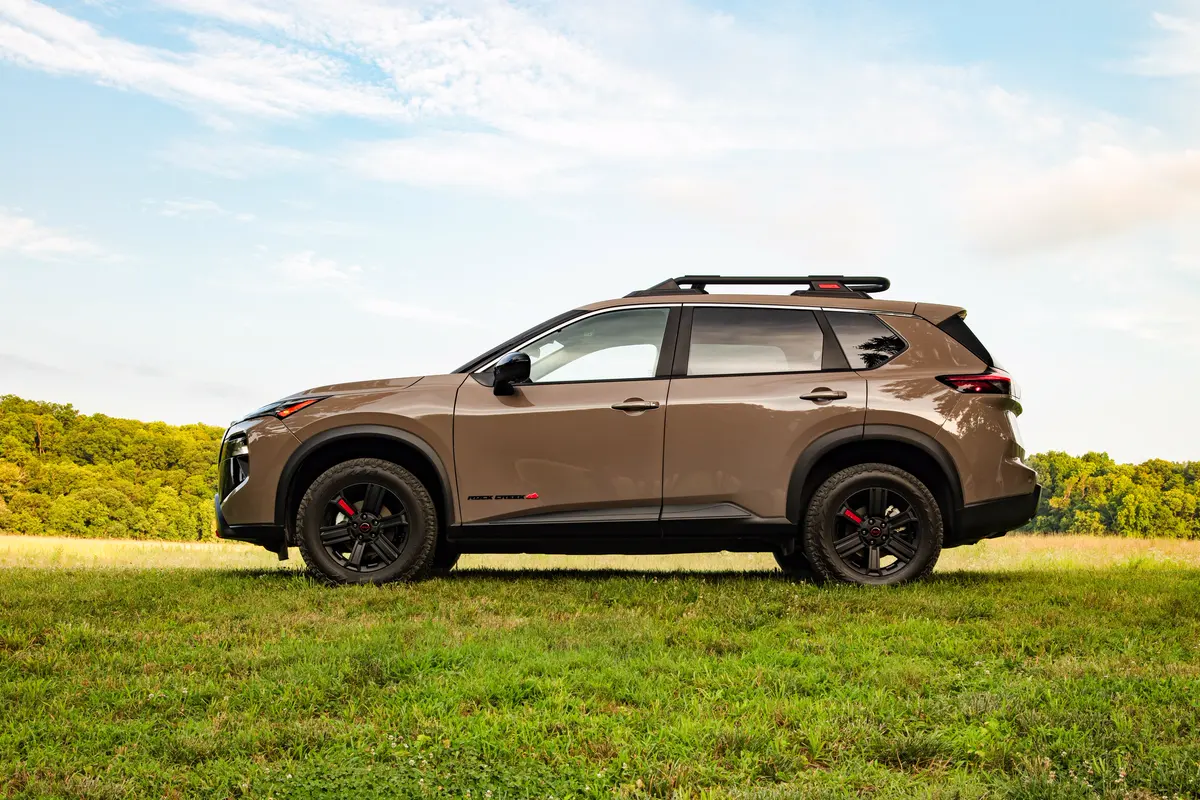 Nissan Rogue Rock Creek beige vu de profil dans un pré